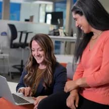 Illustrative photo: two colleagues working at a laptop